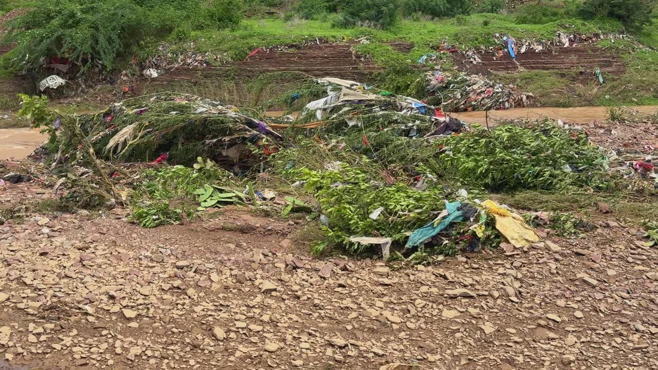 A river affected by flooding and a large amount of waste, including plastic bags and other discarded materials, polluting a body of water or a flood-affected area