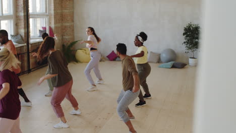 female coach dancing with group of multiethnic students in studio