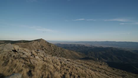 cinematic pan shot gigantic landscape with rocks and mountains during blue sky and sunlight