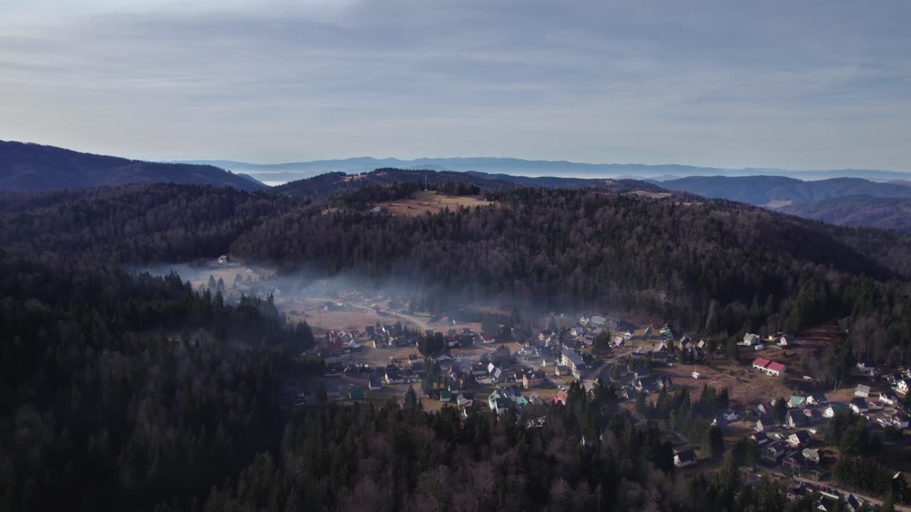 vista aérea de un pueblo en medio de un bosque cubierto de smog