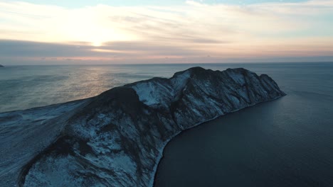 snowy mountains at sunset over the sea