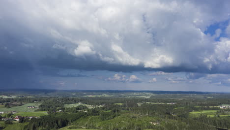 Hiperlapso-Aéreo-De-Nubes-Oscuras-Moviéndose-Sobre-El-Bosque-Y-El-Campo-Del-Sur-De-Noruega---Seguimiento,-Disparo-De-Drones