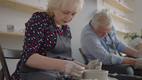 three elderly people work on a potter's wheel in slow motion