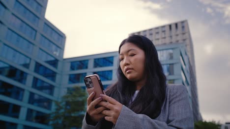 Low-angle-view-of-business-Chinese-woman-holding-mobile-phone