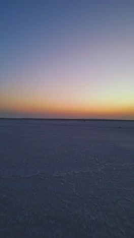a forward-moving aerial view of the endless white rann of kutch in gujarat a vast salt desert stretching endlessly beneath a glowing evening sky capturing the serene beauty of this natural wonder 4k