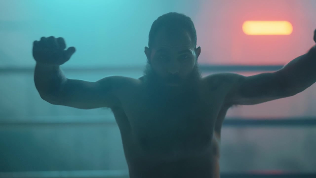Slow Motion of a Muscular Man Stretching in a Dramatic Boxing Ring
