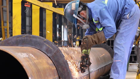 ironworker polishing welded spots on steel surface with a grinder