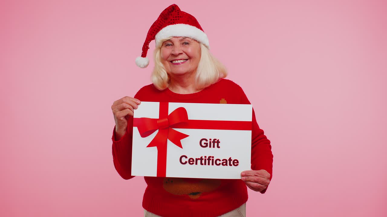 anciana abuela mujer con suéter de año nuevo presentando tarjeta certificado de regalo cupón ganador