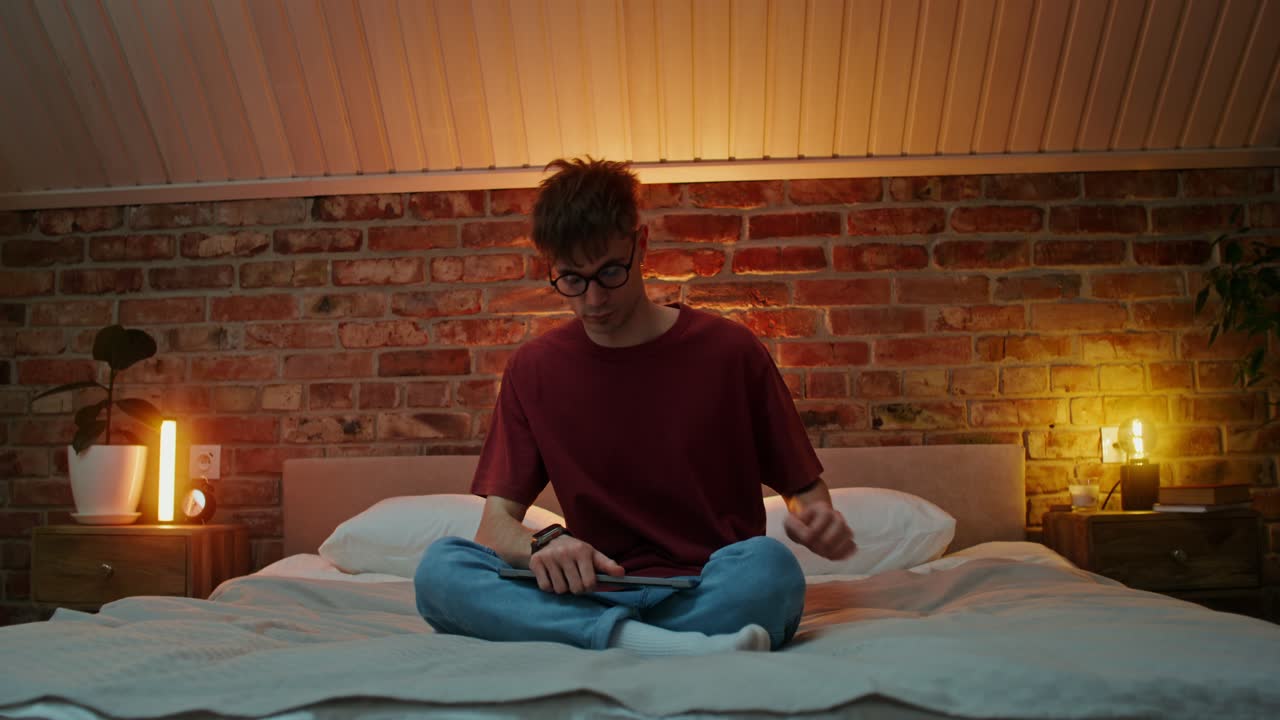 젊은 남자가 아한 침실에서 노트북에서 일하고 있습니다.