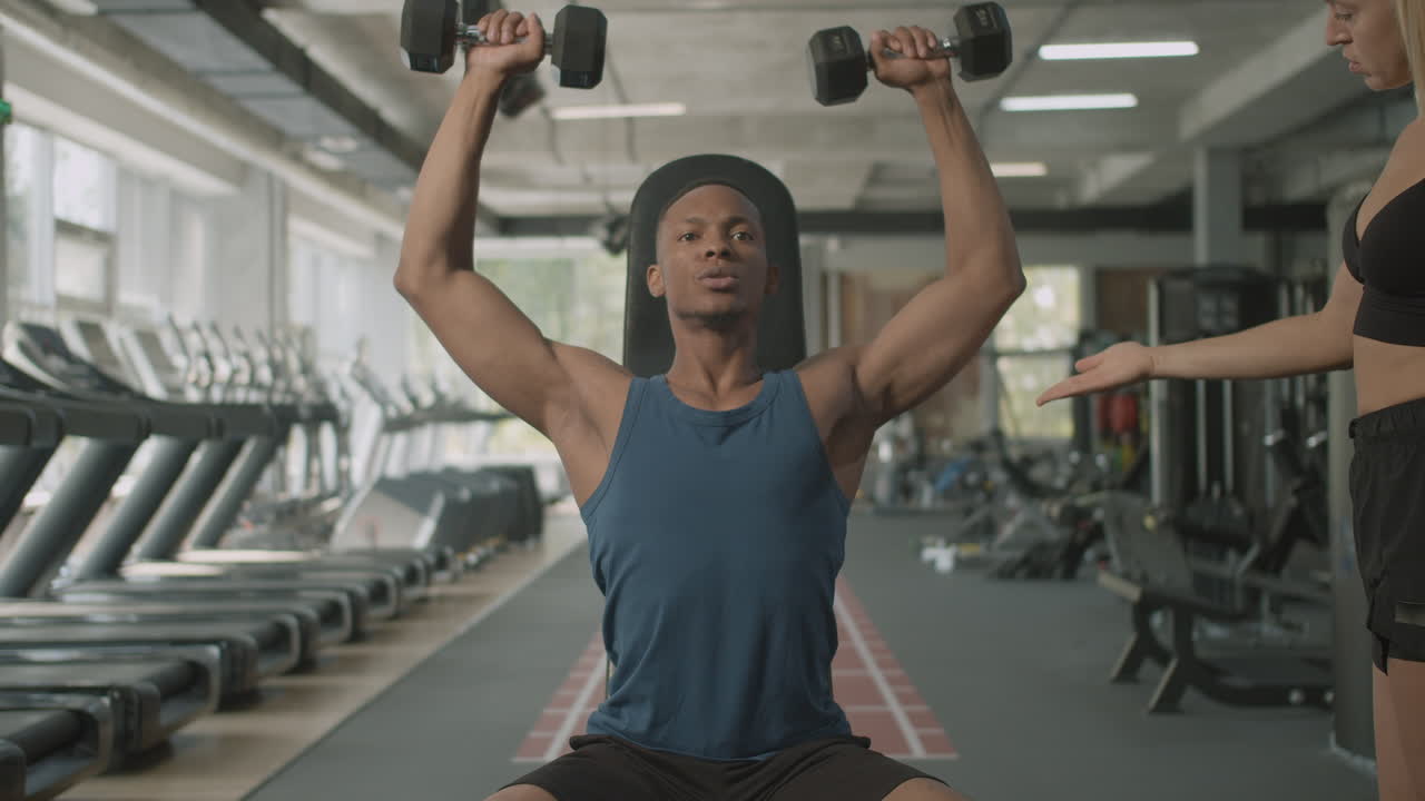 코카시안 여성 모니터와 체육관에서 운동하는 아프리카계 미국인 남자의 앞면.