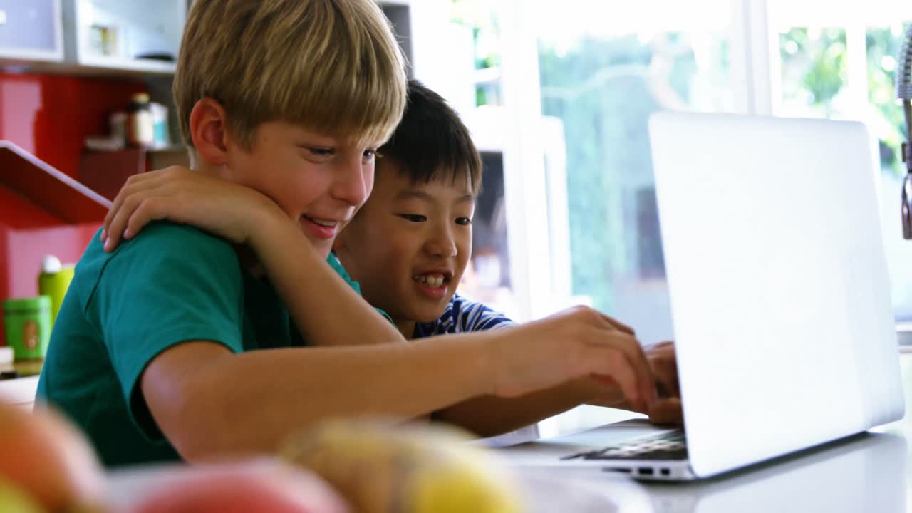 hermanos usando computadora portátil en la cocina