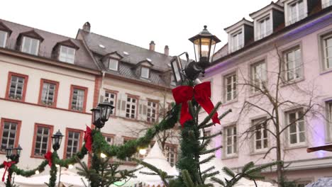 Weihnachtsrote-Schleife-Und-Grünes-Lametta-Auf-Laternenpfahl-Auf-Dem-Marktplatz-In-Einer-Europäischen-Stadt-Auf-Einem-Festlichen-Weihnachtsmarkt-In-Europa