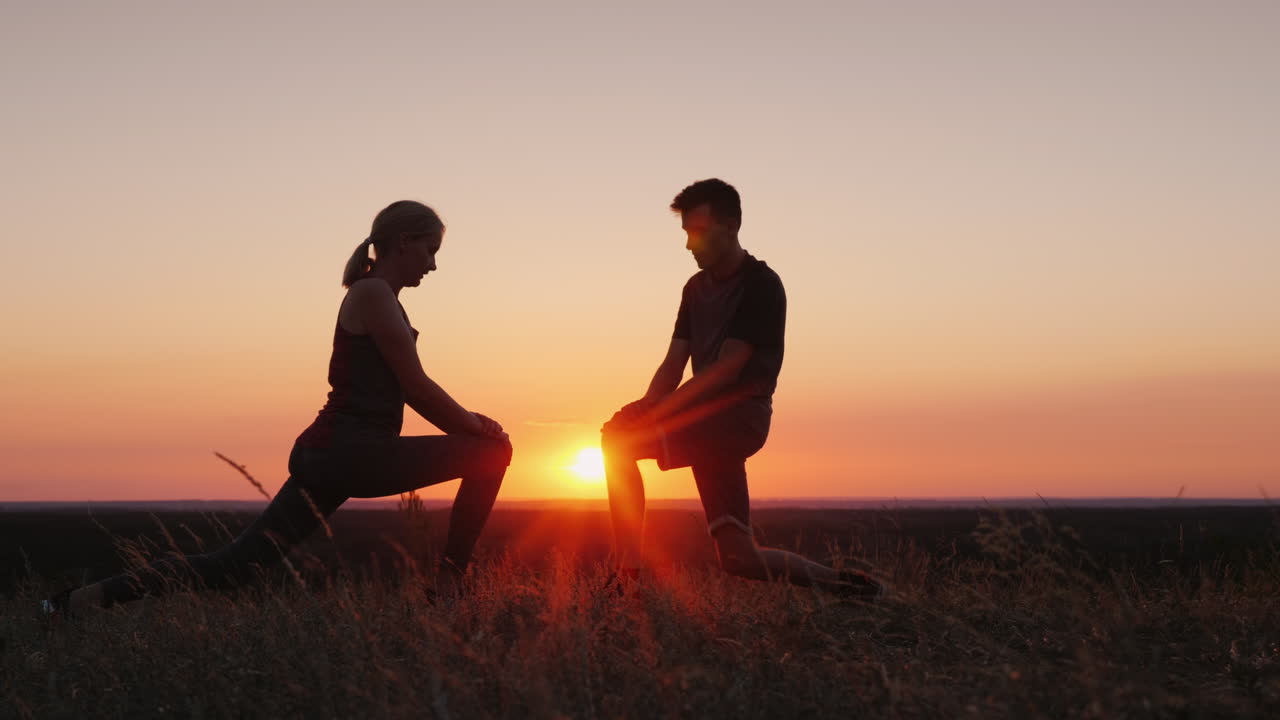 엄마와 그녀의 성인 아들은 아름다운 일몰 환경에서 함께 스포츠를 합니다.