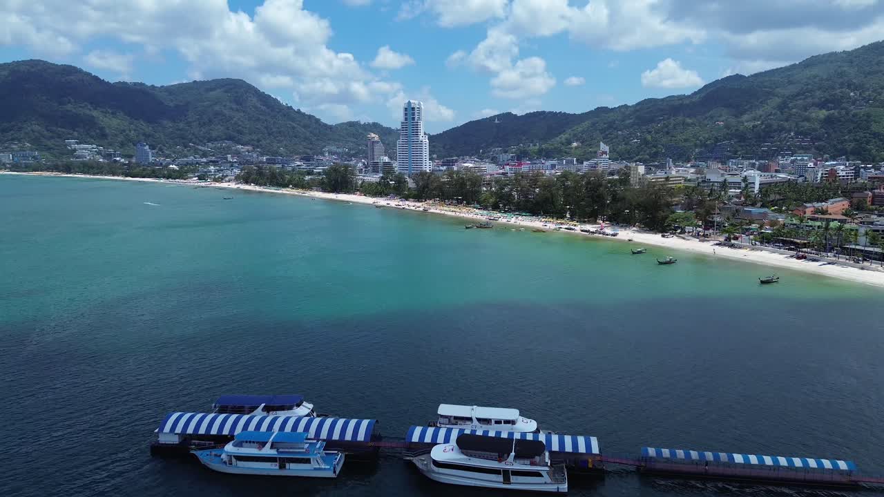 Luftfoto af Patong Beach, der viser en flydende mole med både ankret langs den tropiske kystlinje og klart turkisblåt vand i Phuket, Thailand – et populært rejsemål