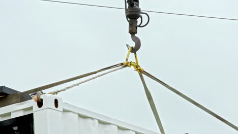 crane lifting a shipping container with straps