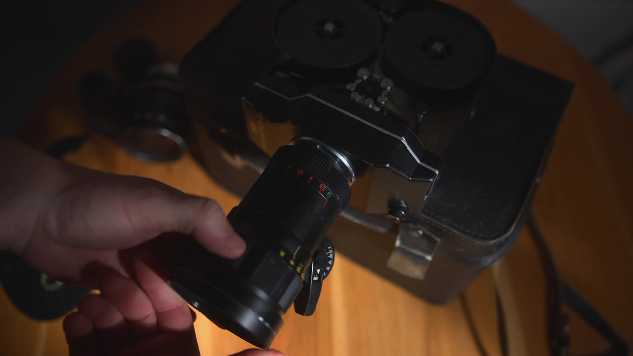 Gros plan sur un projecteur de film vintage centré sur une table en bois, avec un accessoire flou au premier plan et un éclairage doux et chaleureux créant une ambiance rétro nostalgique.