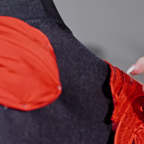 female's hands of the skilled worker pinning beautiful dress to the mannequin. seamstress is pinning the red material to the black dummy. concept sewing and handicraft. close-up