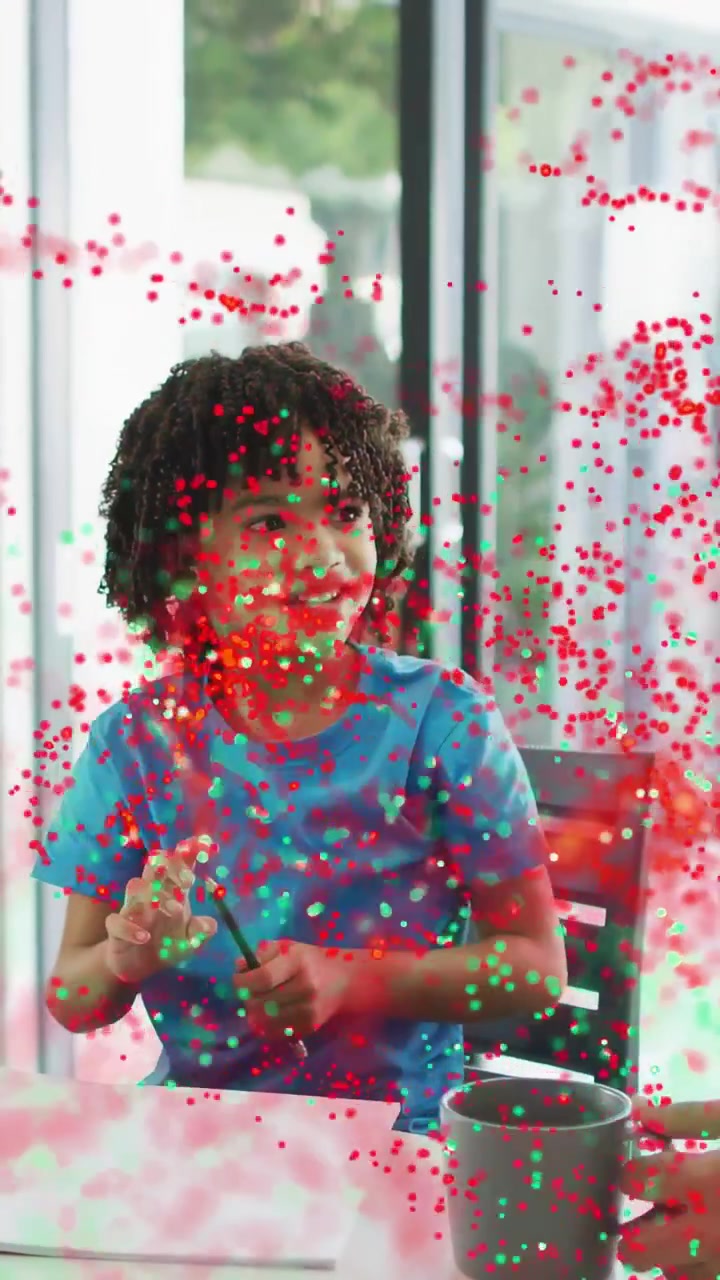 Vertical video: Boy twiddling pen after adult placing gray mug, particles moving over him, learning