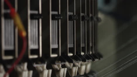 close up on gear of automated textile knitting machinery with cotton threads going inside it, in a factory in china