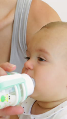 madre alimentando a su niña con un biberón