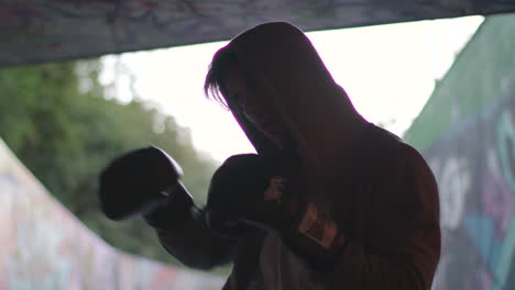 medium shot of young attractive man boxing in underpass, in slow motion