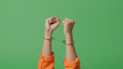 close up of male prisoner's hands in handcuffs being raised on the green screen background