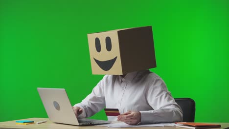 person with box on head using laptop and credit card