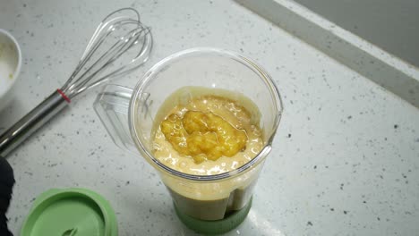 the chef is pouring ingredients into a container and blender for grinding purposes. these ingredients will be thoroughly blended and ready for the next steps.