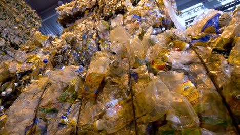 recycling pet bottles collected into big stacks. garbage sorting center. dolly shot.