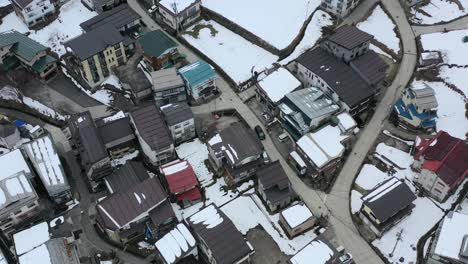 Vista-Aérea-De-Automóviles-En-Japón-Conduciendo-A-Través-De-La-Aldea-De-Nozawa-Onsen-En-Nagano,-Japón-Durante-El-Invierno