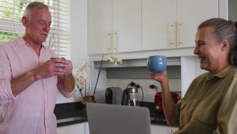 caucasian senior couple drinking coffee together in the kitchen at home