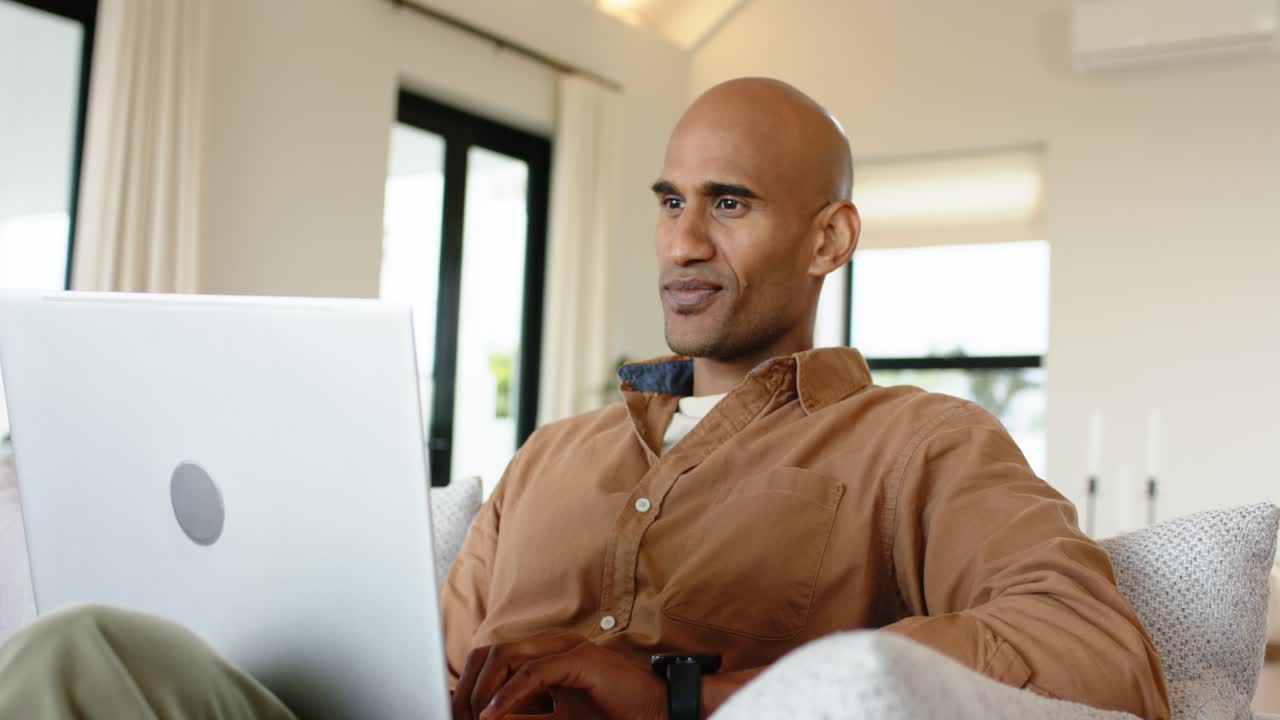 African American man opening laptop leaning in typing response on home sofa closing laptop relaxing