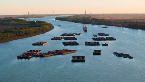 aerial tracking close up shot of anchored barges on a big blue river, clear sunny day, 4k50fps