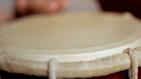 close up of hands of a man playing a drum.