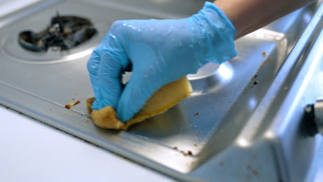 grease removal from stovetop. person wearing a glove wipes down a stovetop to remove grease and food particles, ensuring a clean cooking surface
