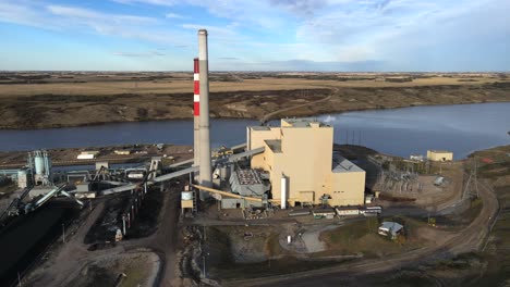 Slow-4k-sideways-flight-over-gas-and-coal-powered-generating-plant-in-rural-Country-setting-during-sunset