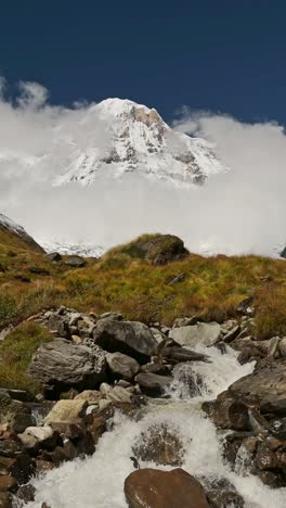 himlayas river and mountains in nepal, vertical video for social media instagram reels and tiktok of a waterfall stream and high altitude mountain river in nepal with snowcapped mountain top landscape