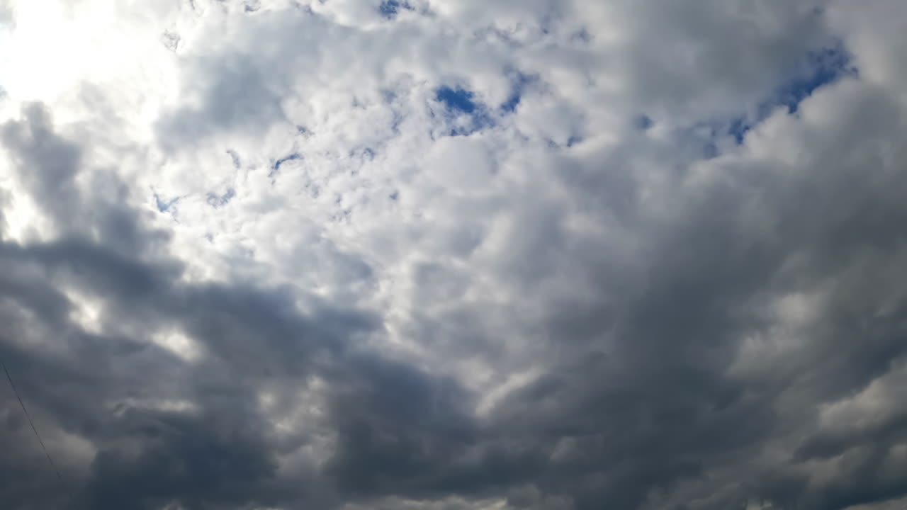 The sky being covered by the grey cloudscape. Low angle view. Rainy clouds accumulate in the atmosphere. Timelapse.