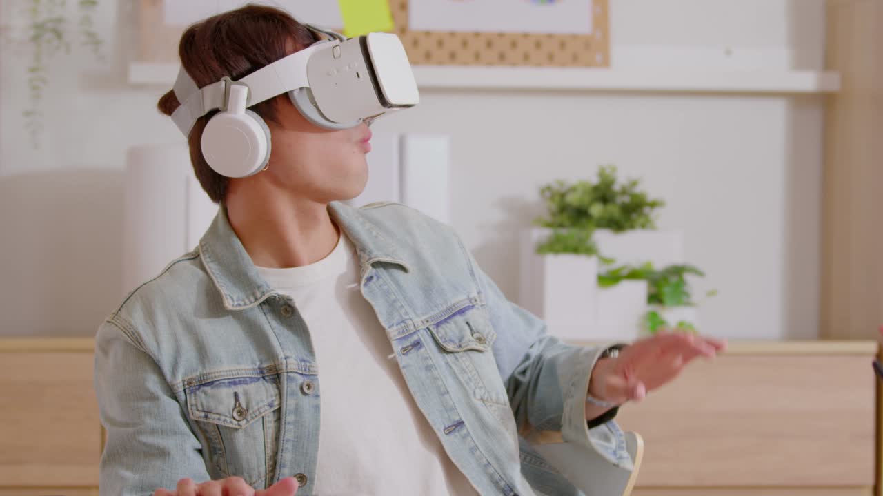 Asian man using VR virtual reality glasses headset excite and amazing in metaverse. Young man goggle using VR enjoy at home enjoying playing watching 360 degree at home.Virtual Reality Metaverse