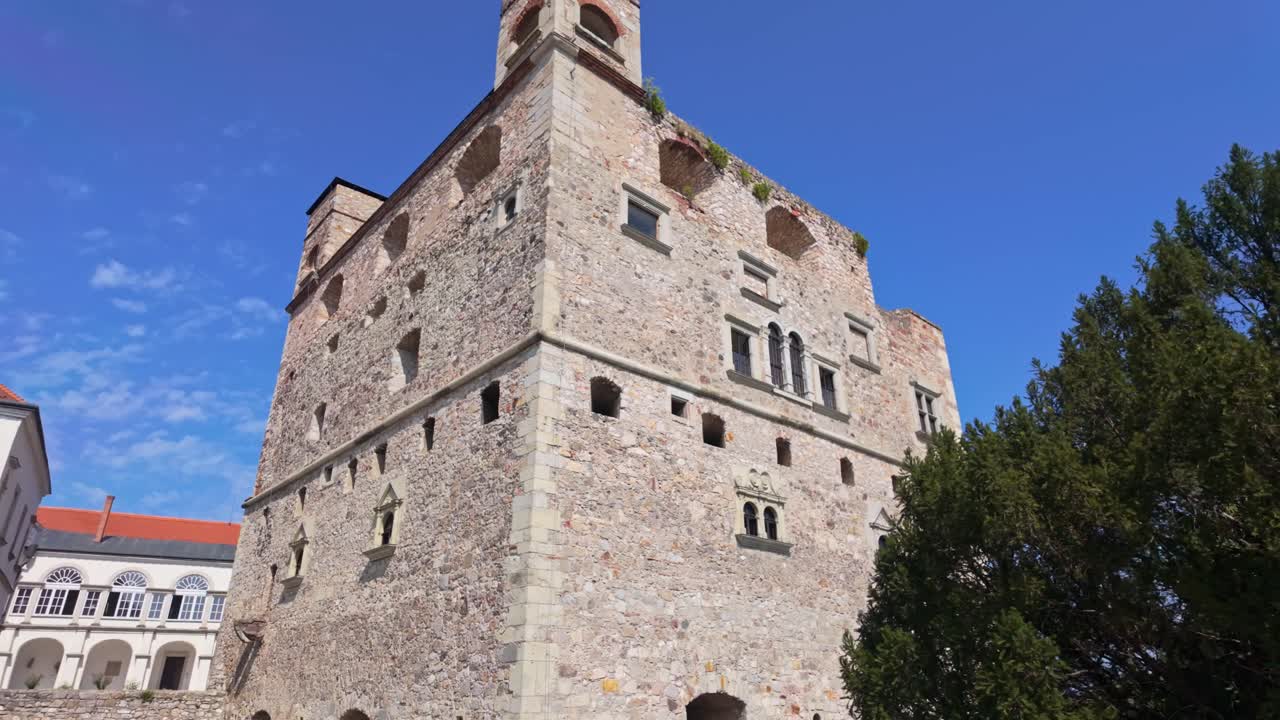 A smooth pan reveals the Red Tower of the Castle of Sárospatak in Hungary, a striking example of late Renaissance architecture set against an autumnal backdrop of trees and sky