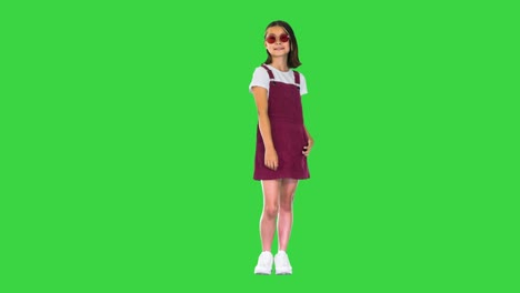 cute little asian girl in sunglasses posing on a green screen, chroma key
