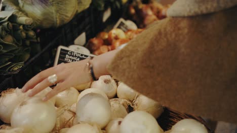 hand of a woman choosing an onion from a grocery store in slow motion