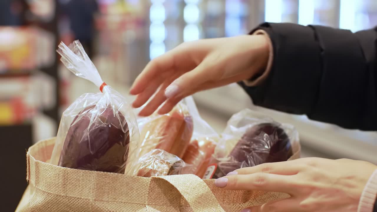 Capturing the Moment of Shopping: A Close-up View of a Hand Placing Packaged Food Items into a Reusable Bag in a Supermarket Setting