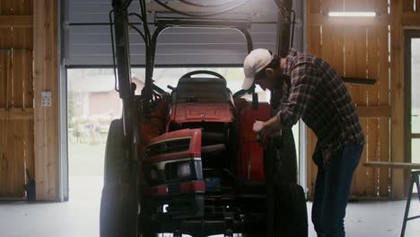 farmer repairing a tractor in a barn