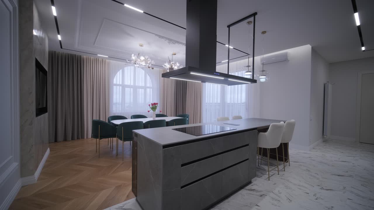 Luxurious open-plan living space with herringbone wood flooring, a marble kitchen island, and a mix of classic and modern lighting fixtures for a chic, airy feel