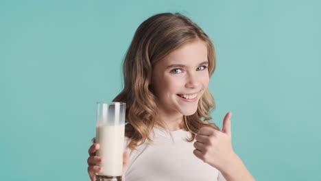 Teenage-Caucasian-girl-in-pijamas-holding-a-glass-of-milk-and-smiling.