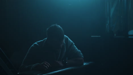 frustrated man sitting in the dark pounds on the table repeatedly