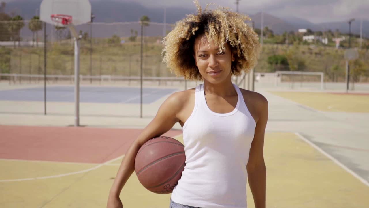 Basketbol topuyla yürüyen genç bir kadın sporcu.