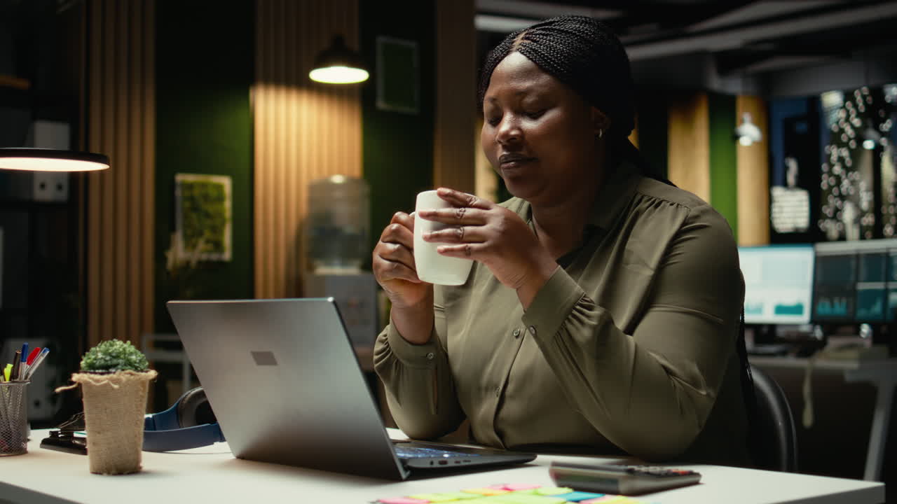 Black woman specialist enjoying a cup of coffee to stay awake late at night