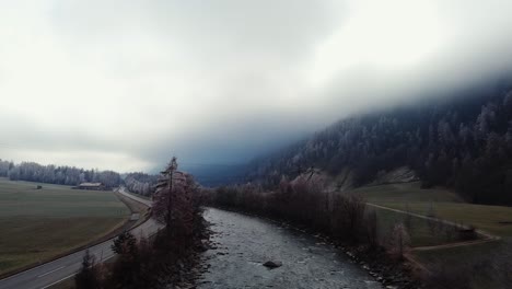 Volando-Sobre-El-Río-En-Un-Paisaje-Aéreo-Rural-De-Niebla,-Campos-Con-Casas-De-Campo-En-El-Día-Nublado-Ötztal,-Austria